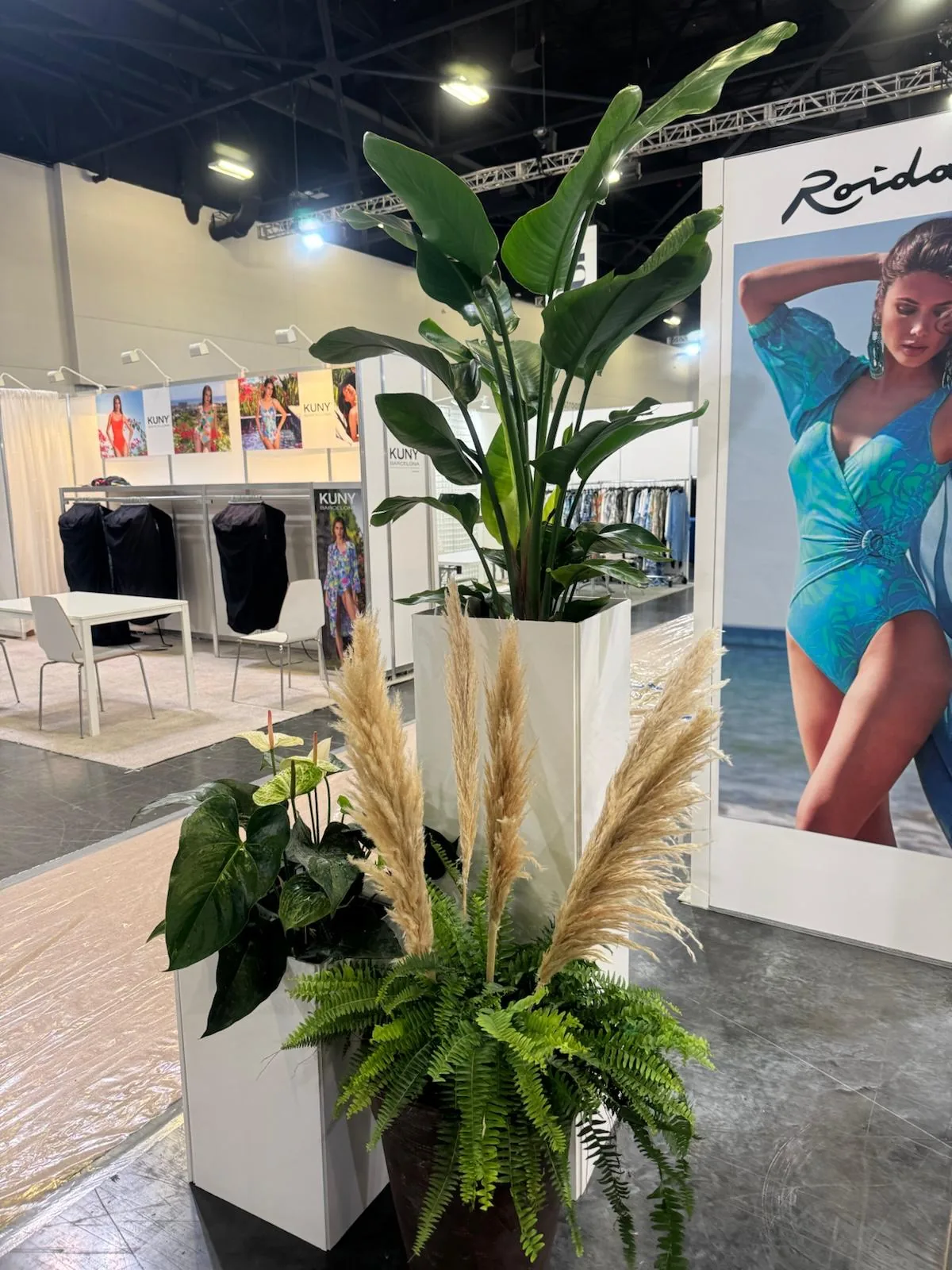 Bird of paradise, ferns and pampas in white planters at a Miami swimwear trade show booth
