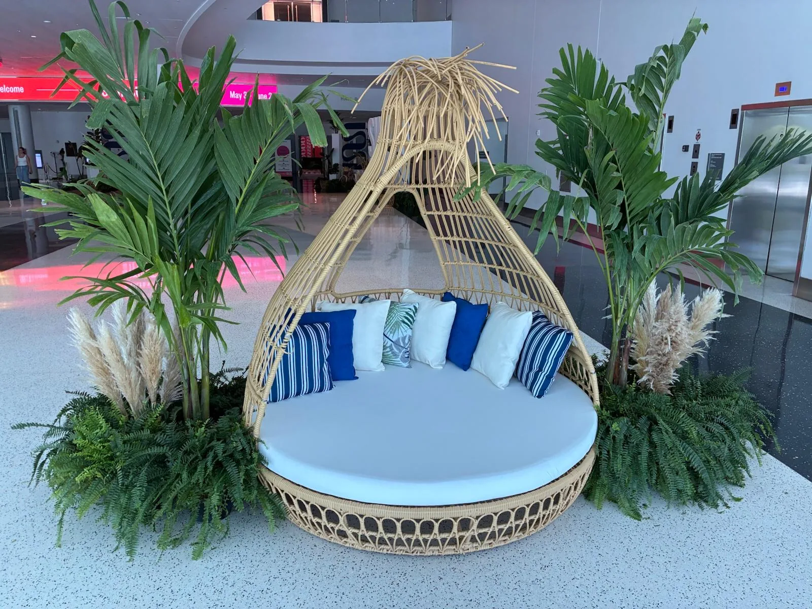 Cabana daybed surrounded by palms and ferns at a resort-style event lounge