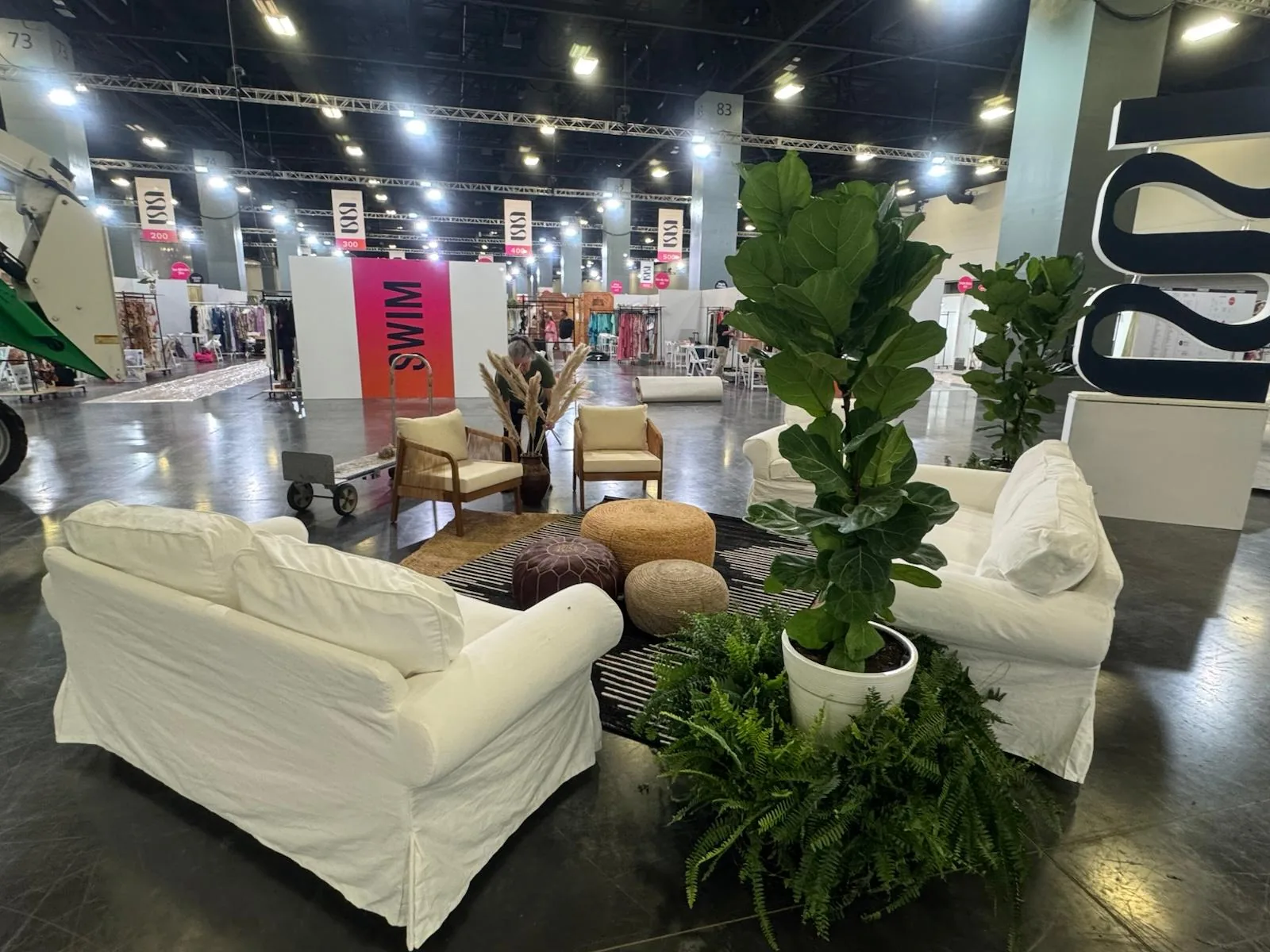 Event lounge with sofas, poufs and fiddle-leaf figs edged in Boston ferns